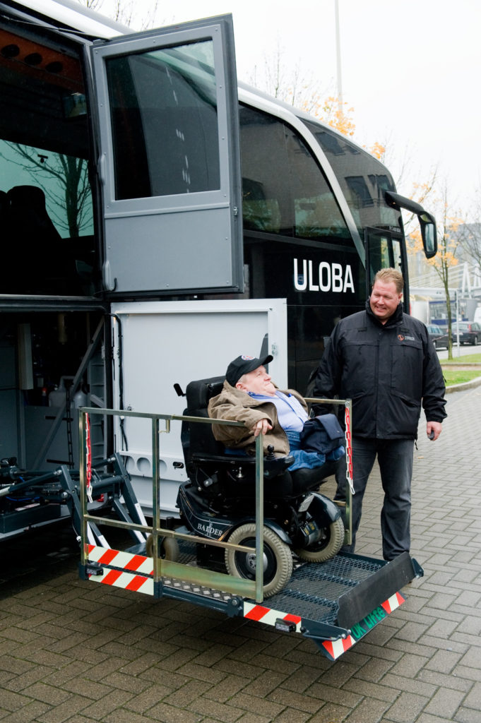 Fornøyd borger i rullestol kjører heisen i bussen